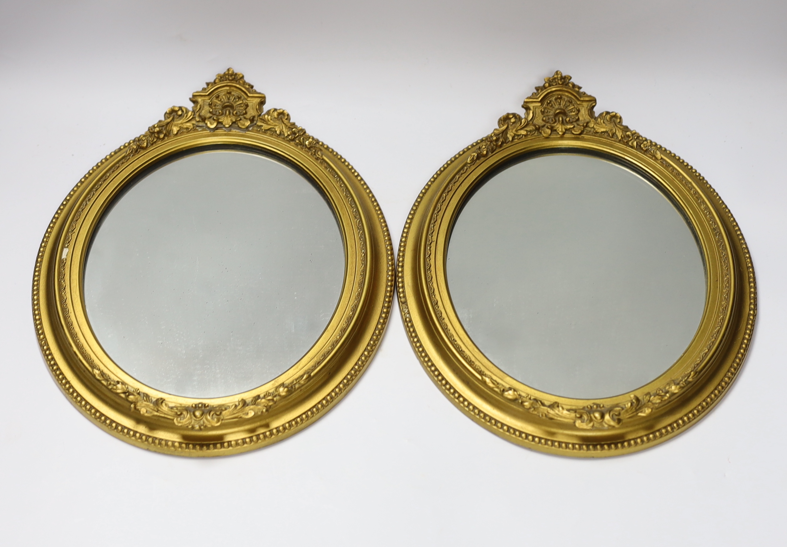 A pair of small oval giltwood and composition wall mirrors, 35cm high